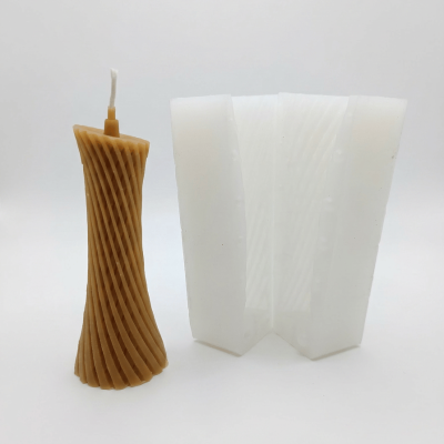 Vela castanha com padrão espiral ao lado de molde de silicone branco