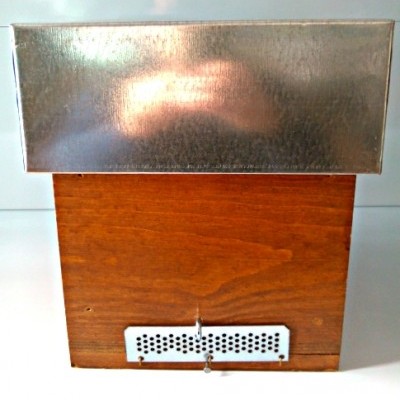 Caixa de madeira com tampa metálica e placa perfurada frontal