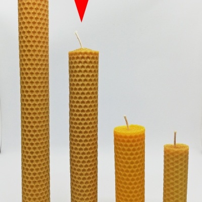 Quatro velas amarelas de cera com textura de favo de mel em várias alturas, seta vermelha aponta para a segunda vela mais alta
