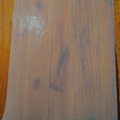 Tela de malha metálica quadrada cinza sobre piso de madeira clara