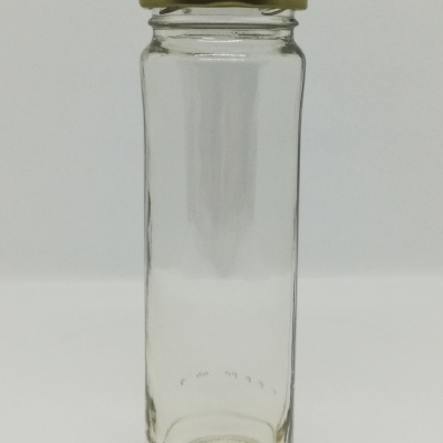 Frasco de vidro com tampa dourada sobre fundo cinza