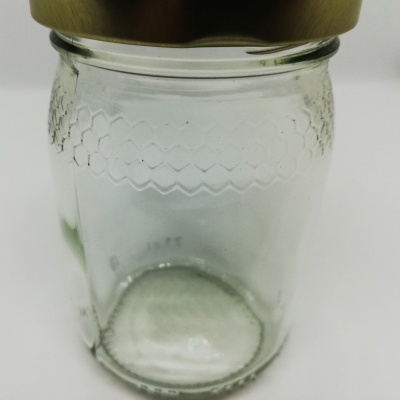 Frasco de vidro transparente com tampa metálica dourada e padrão em relevo