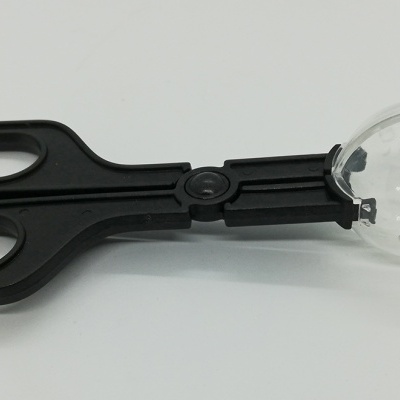 Tesoura preta com colher transparente na ponta sobre fundo branco