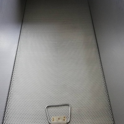 Estrutura metálica cinza com superfície perfurada e duas alças de metal.