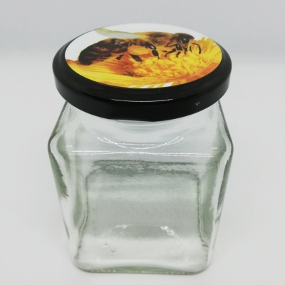 Frasco de vidro transparente com tampa preta decorada com abelha e flor amarela