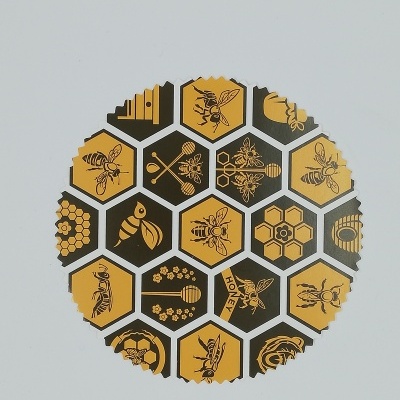 Disco redondo com ilustrações de abelhas e favos de mel em hexágonos amarelos e pretos