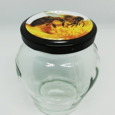 Frasco de vidro com tampa de abelha numa flor amarela