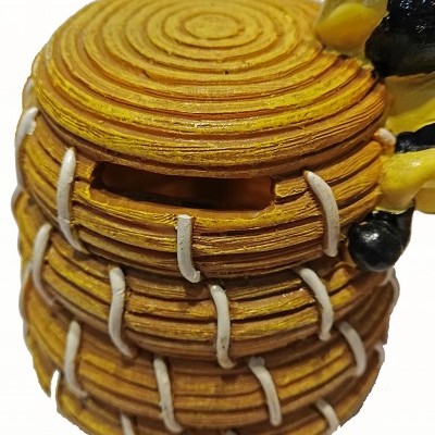 Objeto decorativo amarelo em forma de cesta com cordas brancas e uma abertura retangular