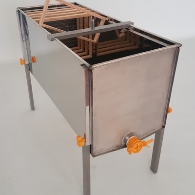 Aparelho metálico retangular com grades internas de madeira e torneira plástica laranja