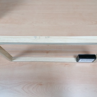 Estrutura de madeira clara com fios metálicos e caixa preta Centinela