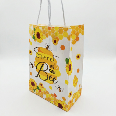 Saco de papel decorado com girassóis, abelhas e padrão de hexágonos amarelos e laranjas
