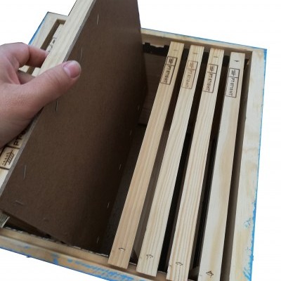 Caixa de madeira com quadros e painel castanho escuro, mão a segurar