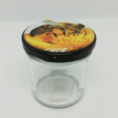 Frasco de vidro com tampa preta e imagem de abelhas em flor