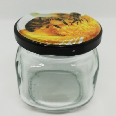 Frasco de vidro com tampa decorada com abelhas e flores amarelas.