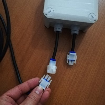 Caixa elétrica branca com cabos pretos e conectores de plástico branco e azul