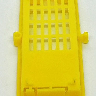 Peça plástica amarela retangular com grelha e encaixes laterais