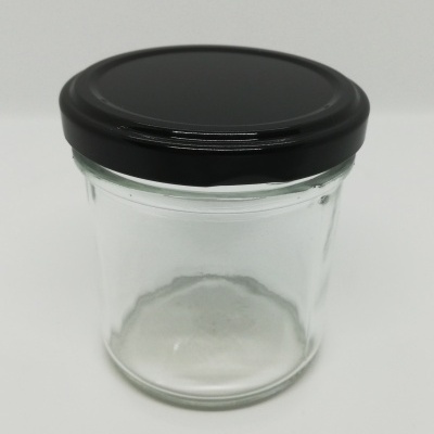 Frasco de vidro transparente com tampa preta sobre superfície branca