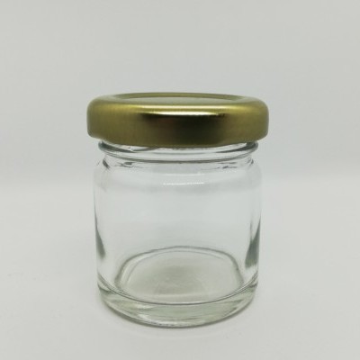 Frasco pequeno de vidro com tampa dourada sobre fundo branco