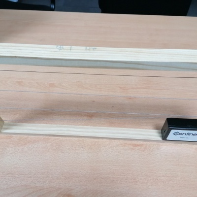 Estrutura de madeira com fios metálicos e dispositivo preto com etiqueta Centinela