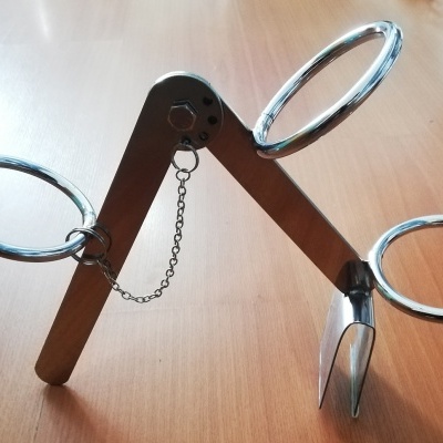 Suporte metálico prateado com três argolas grandes sobre superfície de madeira