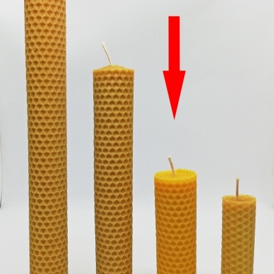 Quatro velas de cera de abelha com textura de favo em fundo branco, seta vermelha aponta para a terceira vela.
