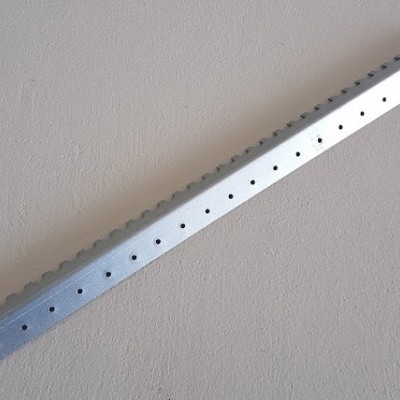 Barra metálica perfurada prateada sobre superfície cinzenta