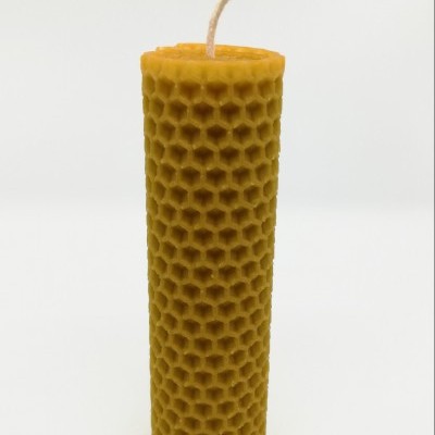 Vela cilíndrica amarela com padrão de favos de mel em fundo branco