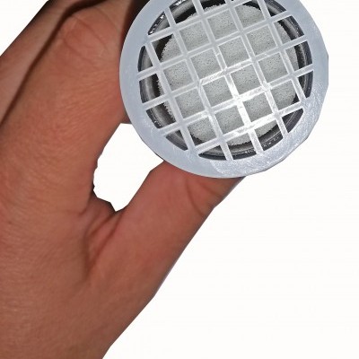 Mão segurando objeto cilíndrico branco com tampa de grelha com espuma