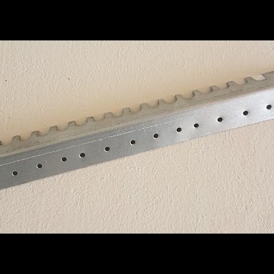 Suporte metálico prateado fosco com orifícios e ondulações sobre superfície bege