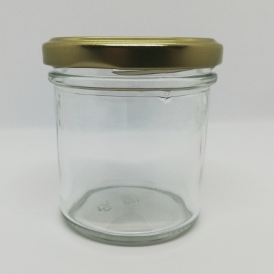 Frasco de vidro transparente com tampa metálica dourada sobre fundo branco