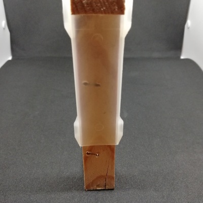 Peça de madeira com capa plástica translúcida em fundo cinza