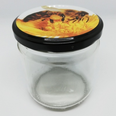 Frasco de vidro com tampa preta e imagem de abelha