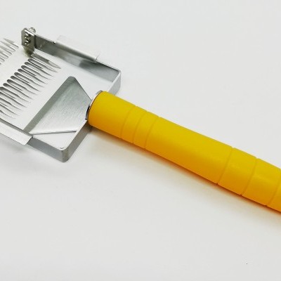 Raspador de lã amarelo com lâminas metálicas em fundo branco