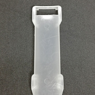 Peça plástica transparente retangular com abertura numa ponta sobre fundo preto