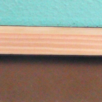 Régua de madeira clara sobre superfície escura com parede azul ao fundo