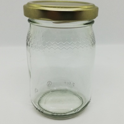 Frasco de vidro transparente com tampa dourada e textura em relevo