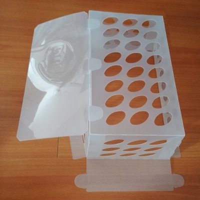 Caixa transparente de plástico rígido aberta com aberturas ovais sobre superfície de madeira.