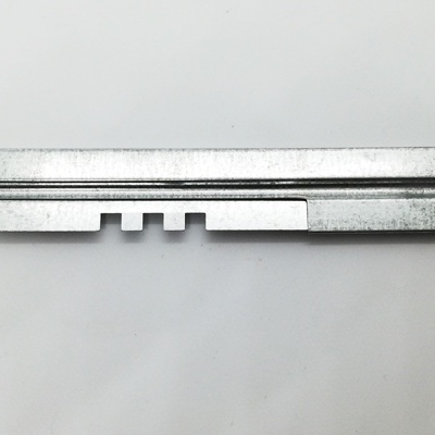 Peça metálica cinza com perfis e furos sobre fundo branco