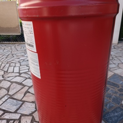 Tambor cilíndrico vermelho com tampa metálica branca e rótulos