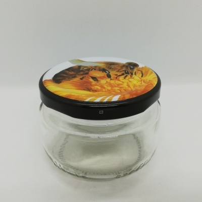 Frasco de vidro com tampa decorada com abelha sobre flor amarela