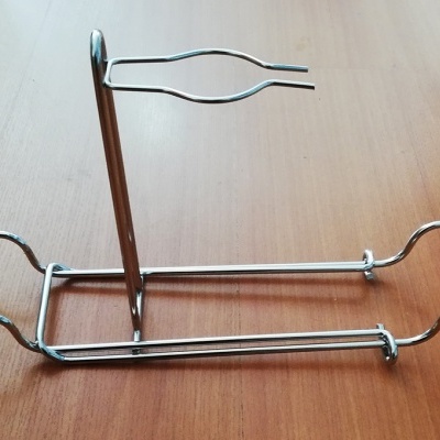 Suporte metálico prateado com formas onduladas em superfície de madeira clara