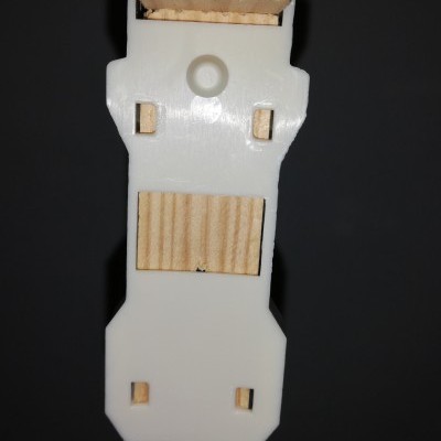 Peça de madeira clara com placa branca de plástico e encaixes