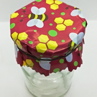 Frasco de vidro com tampa decorada com padrão de abelhas e hexágonos amarelos