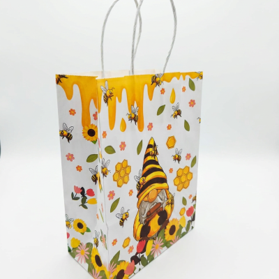 Saco de papel colorido com ilustrações de abelhas, flores e gnomo, com alças brancas