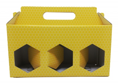 Caixa de cartão amarelo com padrão de células hexagonais e três recortes hexagonais frontais.