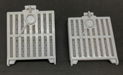 Dois filtros brancos de plástico com padrão de colmeia cinzenta e desenho de lupa