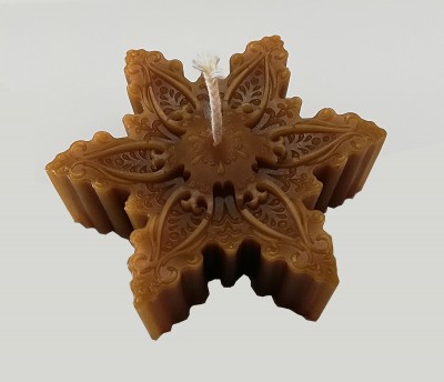 Vela decorativa castanho claro em forma de floco de neve com detalhes gravados.