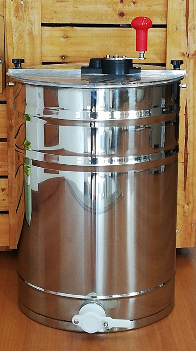 Dispositivo cilíndrico metálico com manivela vermelha e torneira branca sobre chão de madeira