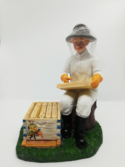 Figura decorativa de apicultor com equipamento e colmeia sobre base verde