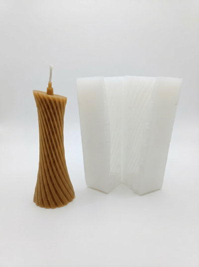 Vela castanha com padrão espiral ao lado de molde de silicone branco